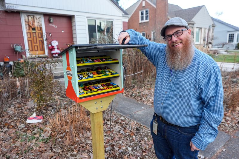 Jim Krom, 54, of Huntington Woods, who works in the automotive industry, filled a Little Free Library-type box with Hot Wheels toy cars. He was photographed on Thursday, Jan. 8, 2026 on the front lawn of the home he inherited from his grandparents, Krom says he comes from generations of engineers dating back to his grandfather, who built grandfather clocks.