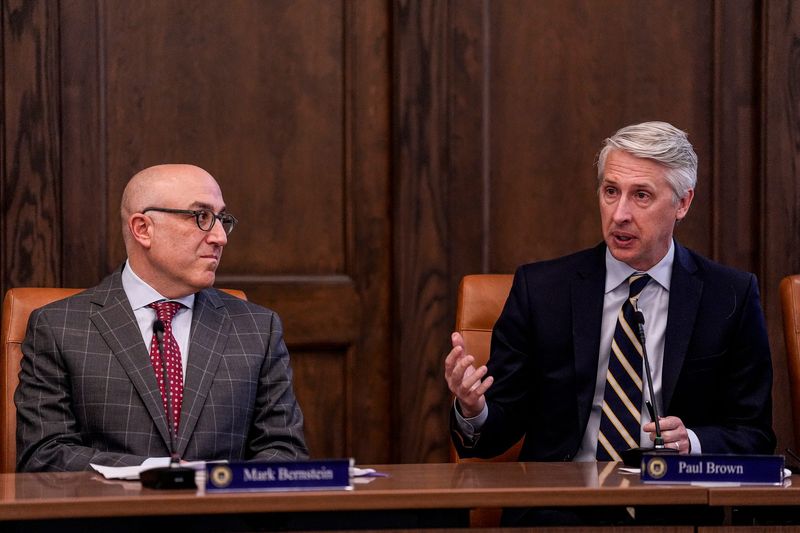 U-M Regent Paul W. Brown, right, congratulates newly appointed president Kent Syverud (not in the photo) next to Regent chair Mark J. Bernstein during a special regents meeting at University of Michigan’s Ruthven Building in Ann Arbor on Monday, Jan. 12, 2026.