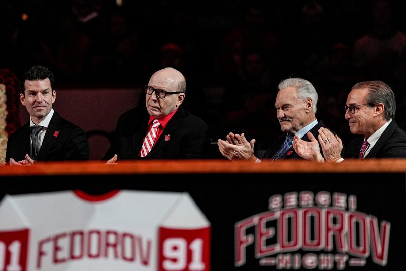 Vladimir Konstantinov, center left, applauds, next to Ryan Gustafson, President and CEO of Ilitch Sports + Entertainment, left, and Mickey Redmond, and Ken Daniels during Sergei Fedorov’s jersey retirement ceremony at Little Caesars Arena in Detroit on Monday, Jan. 12, 2026.