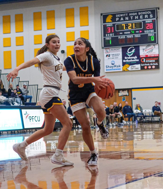 Haslett's Christina Dixon (3) goes to the basket as DeWitt's Sophia Beland (14) defends in prep action Tuesday, Jan.13, 2026.