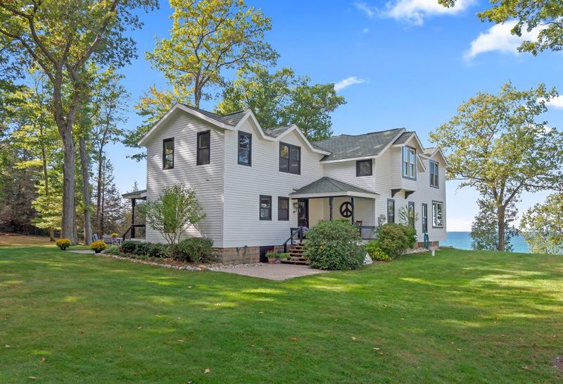 Exterior view of 8282 W. Harrison Road in Golden Township. The 20-acre lakeshore property, featuring a restored farmhouse and custom barn with 687 feet of private sandy Lake Michigan frontage, is listed for sale at $5.7 million.