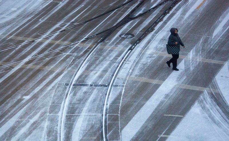A pedestrian crosses East Kilbourn Avenue and North Milwaukee Street as the snow falls in Milwaukee, Wisconsin on Jan. 14, 2026.