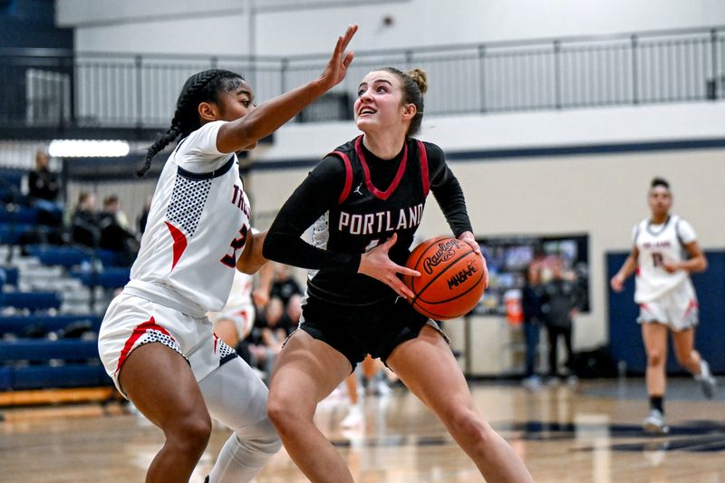 Portland's Lilly Thelen, right, drives to the basket as East Lansing's Olivia Adarkwa defends during the second quarter on Tuesday, Jan. 20, 2026, at East Lansing High School.