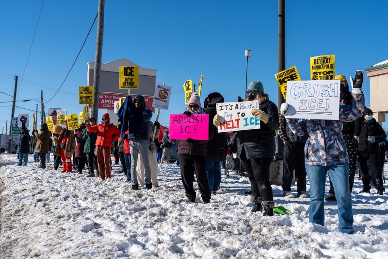 Protesters hold signs while standing on icy pavement during a demonstration led by the Party for Socialism and Liberation Detroit in Detroit on Friday, Jan. 30, 2026. Demonstrators braved winter conditions as they called for an end to federal immigration enforcement actions