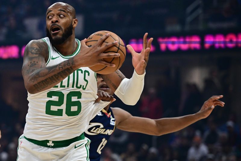 Nov 30, 2025; Cleveland, Ohio, USA; Boston Celtics forward Xavier Tillman (26) grabs a rebound away from Cleveland Cavaliers forward De'Andre Hunter (12) during the first half at Rocket Arena. Mandatory Credit: David Dermer-Imagn Images