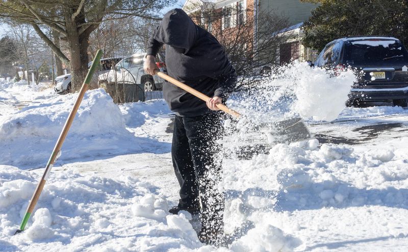 Sergio Tavera shovels a neighbors frozen sidewalk with friend Divine Bey for some extra cash as people continue to try and dig out from last week's snow storm in Barnegat, New Jersey on Saturday, February 7, 2026.
