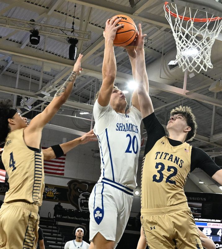 Catholic Central's Gideon Gash splits the defense of St. John’s Ethan James and Jack Goodnough in the CHSL basketball finals at Oakland University in Rochester, Michigan on February 13, 2026.