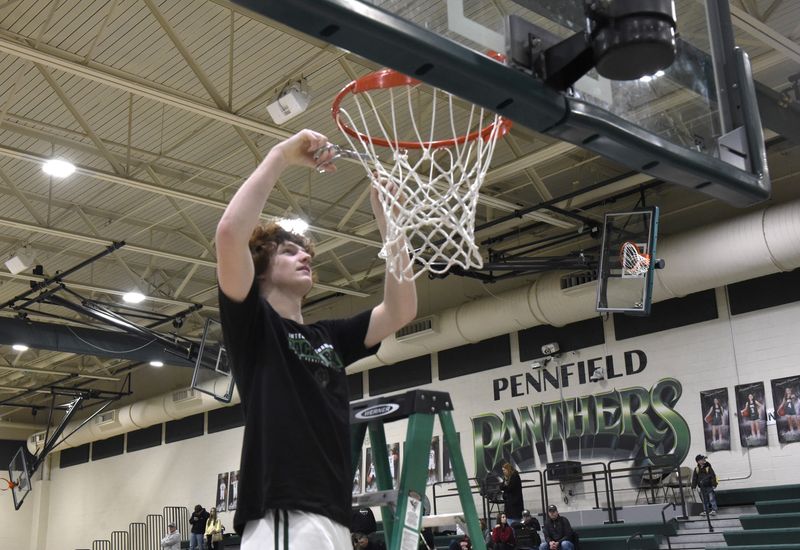 Pennfield senior Calvin Paesens cuts down the net in a championship ceremony following a 48-46 win over Hastings on a night that the Panthers celebrated winning a share of the Interstate 8 Conference title for the second year in a row.