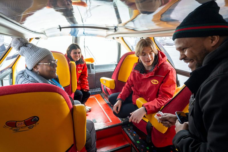 Lolo Mosley of Detroit, 52, left, and DeShaun Gavin of Highland Park, 38, right, talk with Wienermobile drivers Bridget Doyle, 23, second from left, and Ben Kapp, 22, on Monday, Feb. 9, 2026, in Detroit.