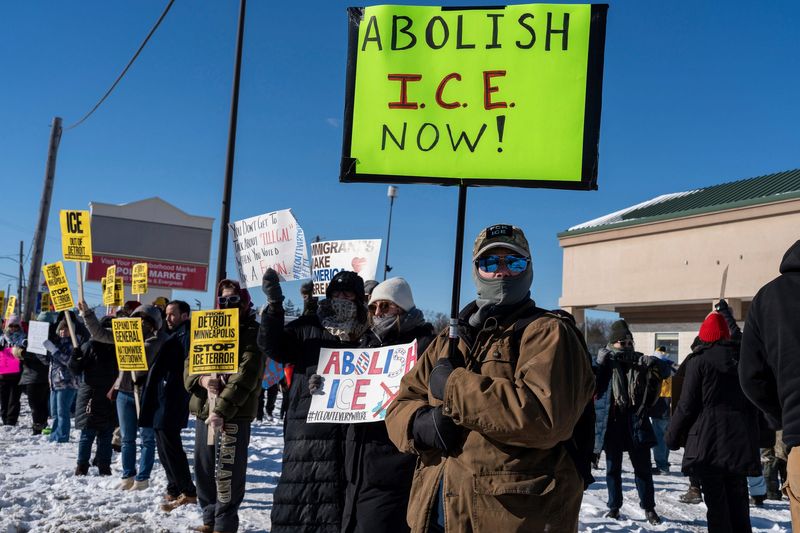Protesters hold signs while standing on icy pavement during a demonstration led by the Party for Socialism and Liberation Detroit in Detroit on Friday, Jan. 30, 2026.