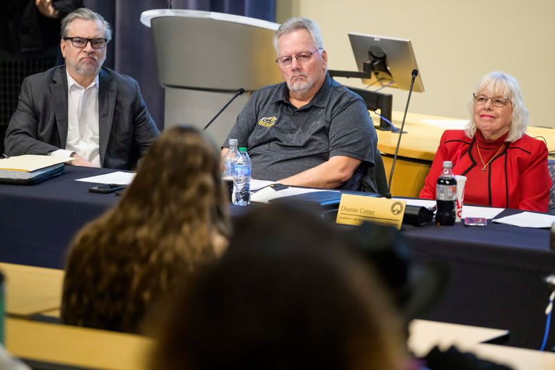 From left, Carey A. DeWitt, interim legal counsel for the Mott Community College Board of Trustees, Jeffrey Swanson, Chairperson of the Board of Trustees, and Dianne Cotter, Assistant to the Secretary of the Board of Trustees, listen as people give public comment during a special meeting of the Mott Community College Board of Trustees on Wednesday, Feb. 18, 2026 at the school in Flint.