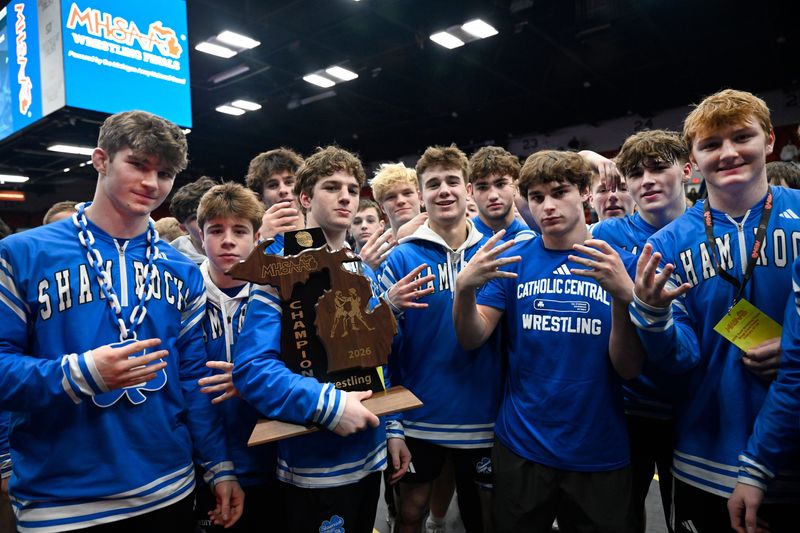 The Detroit Catholic Central wresting team celebrates with its trophy after defeating Hartland 43-16 for the MHSAA Division 1 state team title.