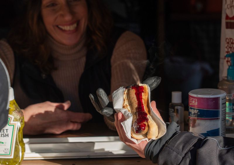 Chic Drozdrowski, 57, of Paradise, hands a customer one of her trademark blueberry bratwursts on Thursday, Feb. 12, 2026.