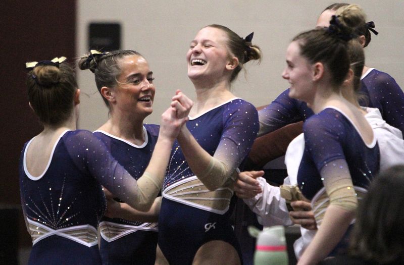 Hartland's Kate Gostlin is congratulated by teammates after scoring a 9.8 on vault during the team state gymnastics meet on Friday, March 6, 2026 at Milford High School.