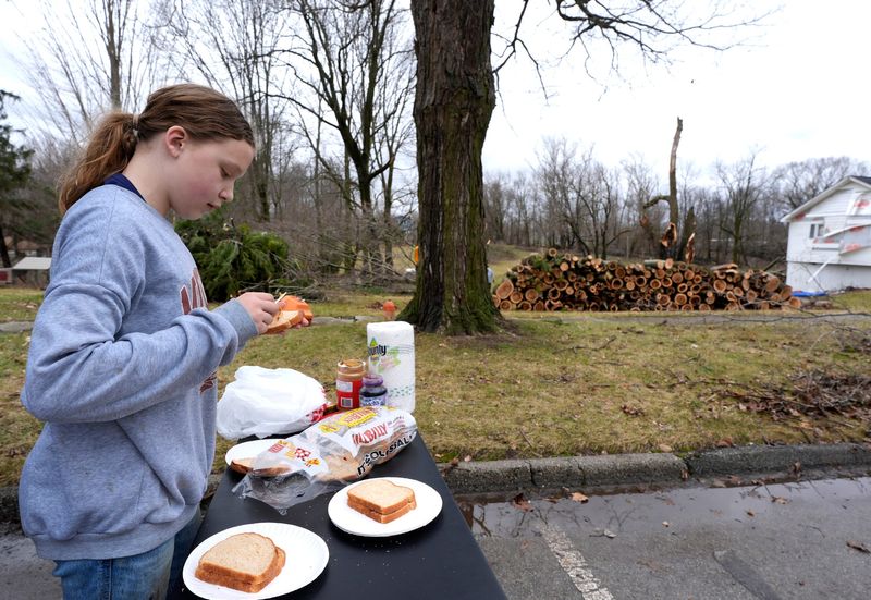 As more grocery supplies come in, Evelyn Peters, 11, of Marshall, makes peanut butter and jelly sandwiches for people on Division Street in Union City on Saturday, March 7, 2026. Peters and others in the community and surrounding areas have come to Union City to help out others whose homes and businesses were damaged or destroyed by the late afternoon tornado that hit the small town the day before.