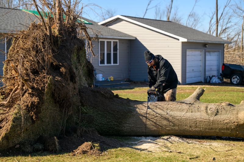 Nolan Ender slices up a downed tree in front of a home owned by Amy Katz on Tuttle Road in Union City, March 8, 2026. Four people were killed and several others were injured when a tornado ripped through southwest Michigan on Friday afternoon.