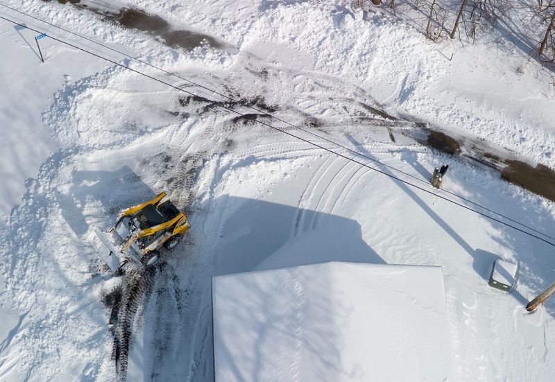 A skid steer clears drifting snow from a driveway Monday, March 16, 2026 just north of Fond du Lac, Wisconsin. The area received about eight inches of snow from the spring storm.