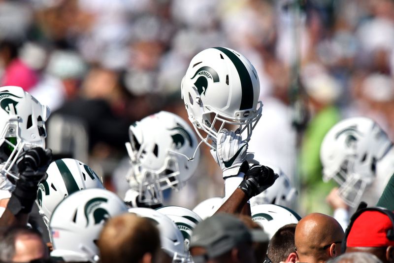 Spartans hold aloft their new white helmets as MSU hosts Western at Spartan Stadium on Saturday, Sept 9, 2017 in East Lansing. (Dale G Young/The Detroit News) 2017.