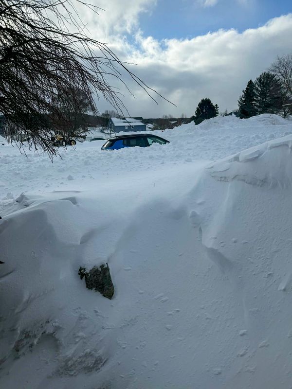 A car is seen just peeking over the top of a huge snow drift in Munising in the UP on Tuesday morning, March 17, 2026 after a historic snow fall. Sue Dempsey, of Munising, finally got her driveway plowed out and took a drive around the UP town which is buried in snow.