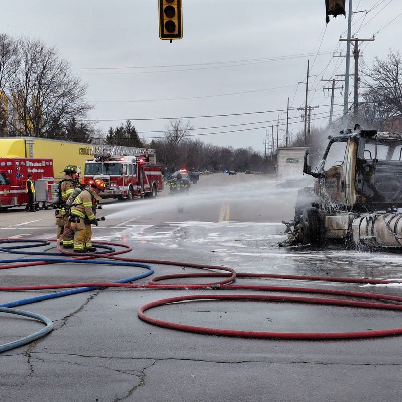 Firefighters hose down a semitractor-trailer involved in a crash that injured nine people and closed a Canton Township intersection for hours on Wednesday, March 18, 2026.