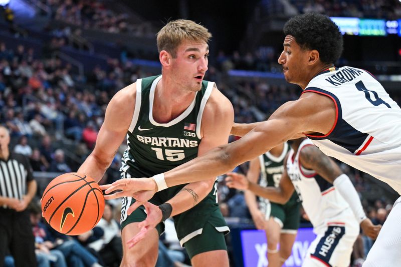 Oct 28, 2025; Hartford, CT, USA; Connecticut Huskies forward Dwayne Koroma (4) knocks the ball away from Michigan State Spartans center Carson Cooper (15) during the second half at PeoplesBank Arena. Mandatory Credit: Mark Smith-Imagn Images