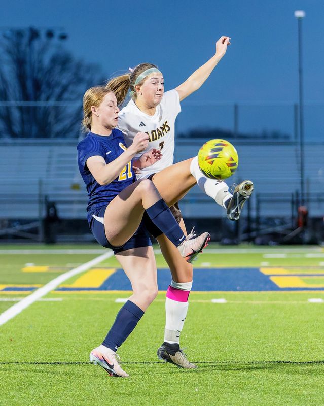 Hartland's Emma Abbott (21) battles Rochester Adams Lexi Calcamuggio for the ball Wednesday, March 25, 2026.