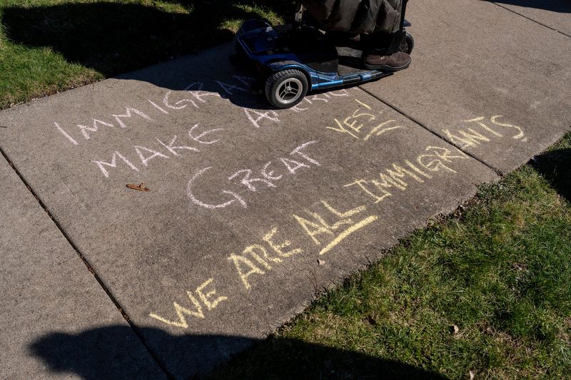 A chalk message reading “Immigrants make America great yes we are all immigrants” is written on a sidewalk during a No Kings protest in Romulus on Saturday, March 28, 2026.