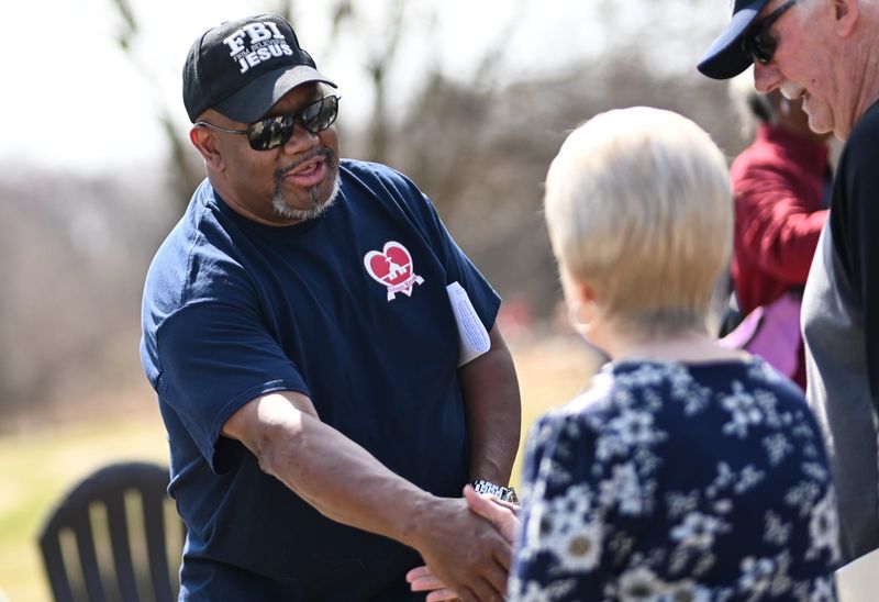 Pastor Michael West of Robinson Memorial Church of God in Christ shakes hands with neighbors, Monday, March 30, 2026, before he held a press conference calling on the city to take action to help keep the 6-acre parcel the church owns near Jolly Road and South Cedar Street where people in the Lansing homeless community have camped. Neighbors say the site is riddled with crime and litter and the fire department has been called for fires several times.