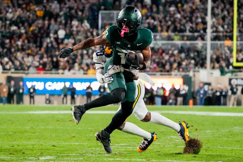 Oct 25, 2025; East Lansing, Michigan, USA; Michigan State Spartans wide receiver Chrishon McCray (13) is tackled after the catch by Michigan Wolverines defensive back Jyaire Hill (20) during the first half at Spartan Stadium. Mandatory Credit: Brendan Mullin-Imagn Images