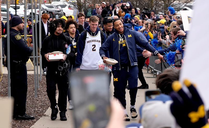 (L to R) Michigan basketball players Elliot Cadeau, Howard Eisley Jr., Charlie May and Nimari Burnett walk to the team bus greeting fans who were lined up in front of the William Davidson Player Development Center at the Crisler Center on the campus of the University of Michigan as the team was getting ready to leave for the Final Four in Indianapolis, Indiana on Wednesday, April 1, 2026.