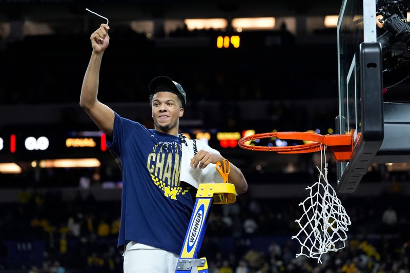 Michigan guard Trey McKenney (1) cuts a piece of the net as the teams celebrates beating Connecticut to win the NCAA national championship at Lucas Oil Stadium in Indianapolis on Monday, April 6, 2026.