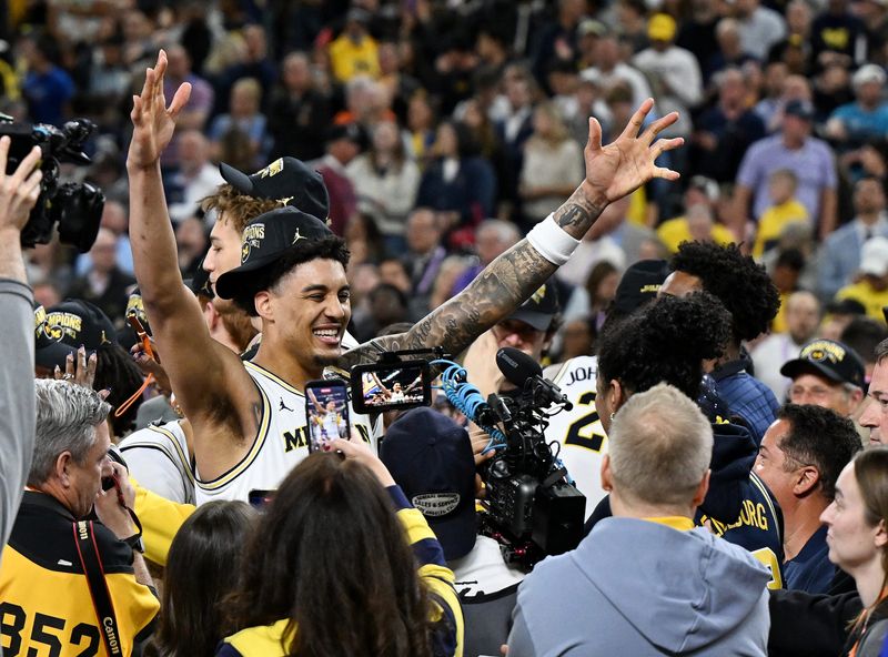 Michigan forward Yaxel Lendeborg, arms up, reacts when he gets ready to embrace his mother, Yissel Raposo, during the postgame celebration after winning the national title.