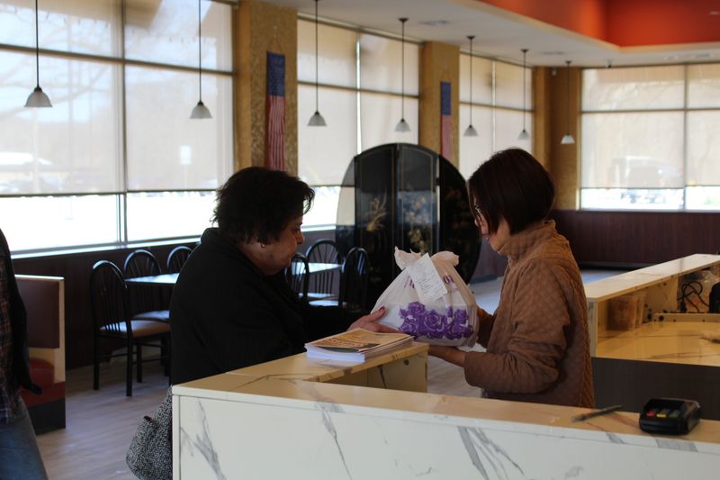 An employee hands an order to a customer at Dragon Express on April 8 in Hamburg Township, with a circular room divider in the background.