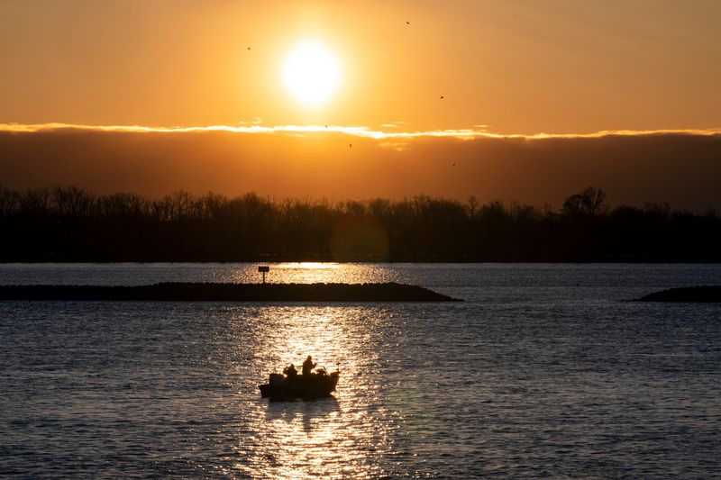 Walleye fishermen drift lazily down the Detroit River as the sun rises behind them, Tues., April 7, 2026, in Grosse Ile, Mich.
