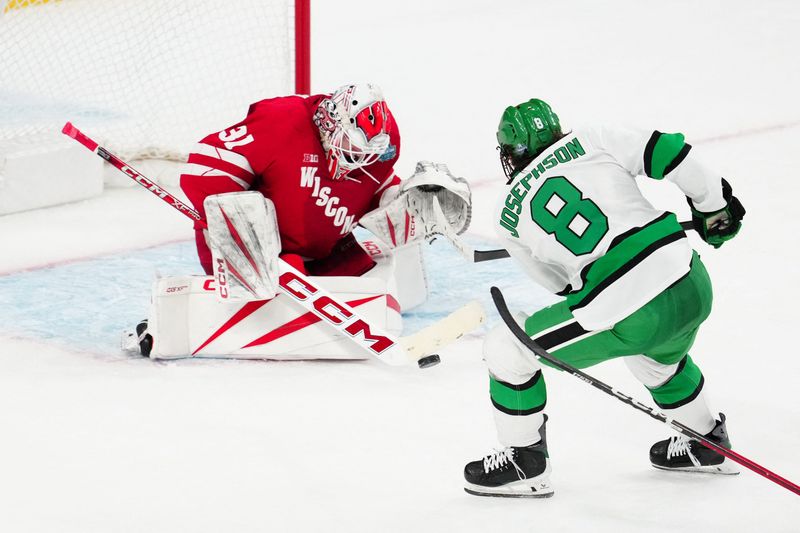 Badgers goalie Daniel Hauser (31) blocks a shot on goal by Fighting Hawks forward Ollie Josephson (8) in the second period in the semifinals of the NCAA men's ice hockey Frozen Four at T-Mobile Arena.