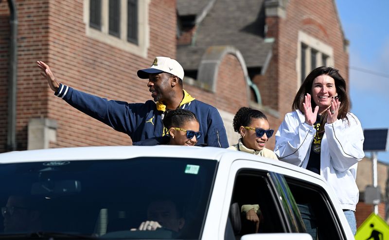 Michigan assistant coach Mike Boynton Jr., left, waves to the crowd riding with his family during the parade for the 2026 Michigan Men’s Basketball National Championship team.