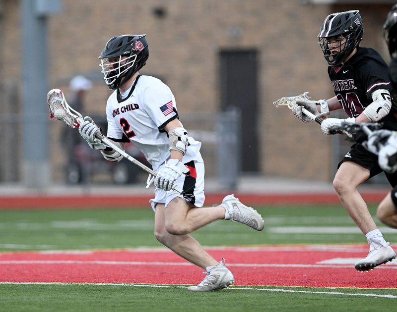 Divine Child senior Gavin Abraham (2) runs with the ball in front of Dexter sophomore Victor Dettling (14) in the first half as Divine Child takes on Dexter in boy’s lacrosse at Divine Child High School on April 13, 2026 in Dearborn, Mich.