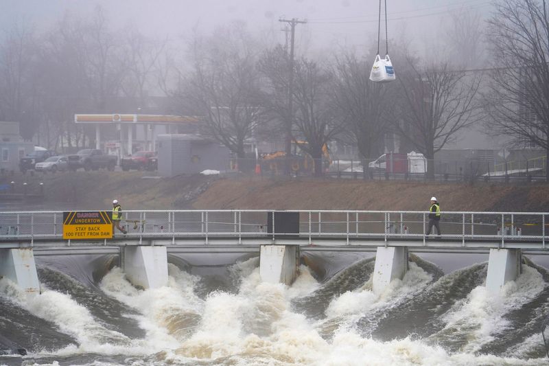 Crews work to reinforce the Cheboygan Dam as water rushes down the Cheboygan River on Tuesday, April 14, 2026.