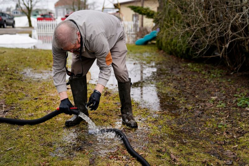 Dave Orr, 65, of Cheboygan works pumping flooded waters out of his mother-in-laws basement on the east side of the Cheboygan River near the Cheboygan Dam on Tuesday, April 14, 2026.