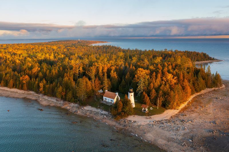 Presque Isle lighthouses: Twin beacons on a fog bound point
On Presque Isle, about 35 minutes north of Alpena, visitors find a bucket list maritime stop where two historic lighthouses and the Keeper's House Museum complement better known Great Lakes institutions like Whitefish Point and the Dossin Museum. On foggy fall mornings, the Old Presque Isle Lighthouse and New Presque Isle Lighthouse emerge from Lake Huron mist as classic 19th century conical towers, the older "Old Light" having served from 1840 to 1870 at the bay entrance with a 30 foot tall white stone and brick tower, visitor center, museum and climbable steps to harbor views. Nearby stand a statue of longtime keeper Patrick Garrity Sr., a set of old style stocks and even the bell from Lansing's demolished Old City Hall clock tower.