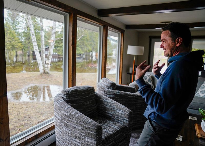 Chad Sackrider, 49, of Williamsburg, Ohio, stands in the living room of his vacation house on the Little Sturgeon River in Indian River on Wednesday, April 15, 2026. Sackrider was relieved that the river seemed to be receding. Some of his neighbors were not so lucky. “We’ve never seen it this high,” he said about regional flooding in the area.