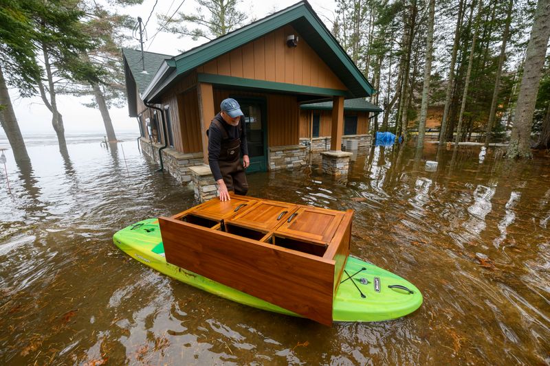 John Stencel uses a kayak to move a piece of funiture from his flooded home on Black Lake in Onaway on Wednesday. Flooding along the lakes and rivers that feed the Cheboygan River was backing up into yards and homes along Black, Mullett and Burt lakes on Wednesday after significant rain fall and a slow snow and ice melt on the lakes and surrounding areas that caused widespread flooding across the northern Lower Peninsula.