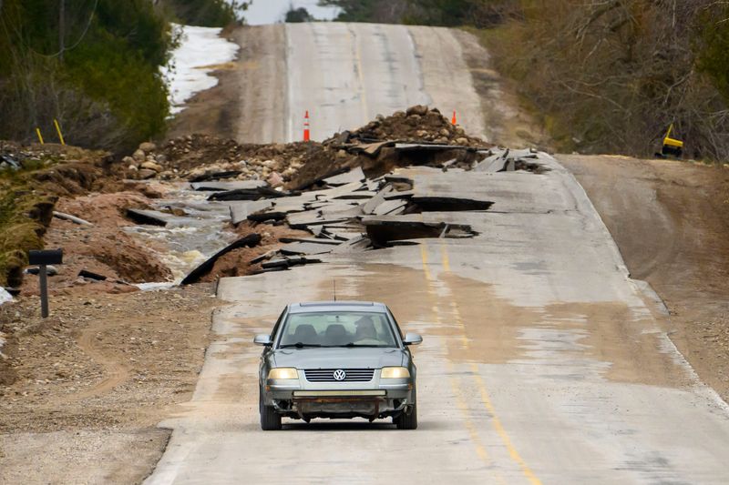 A car drives around a washed out section of road on West Heythaler Highway in Rogers City, April 15, 2026.
