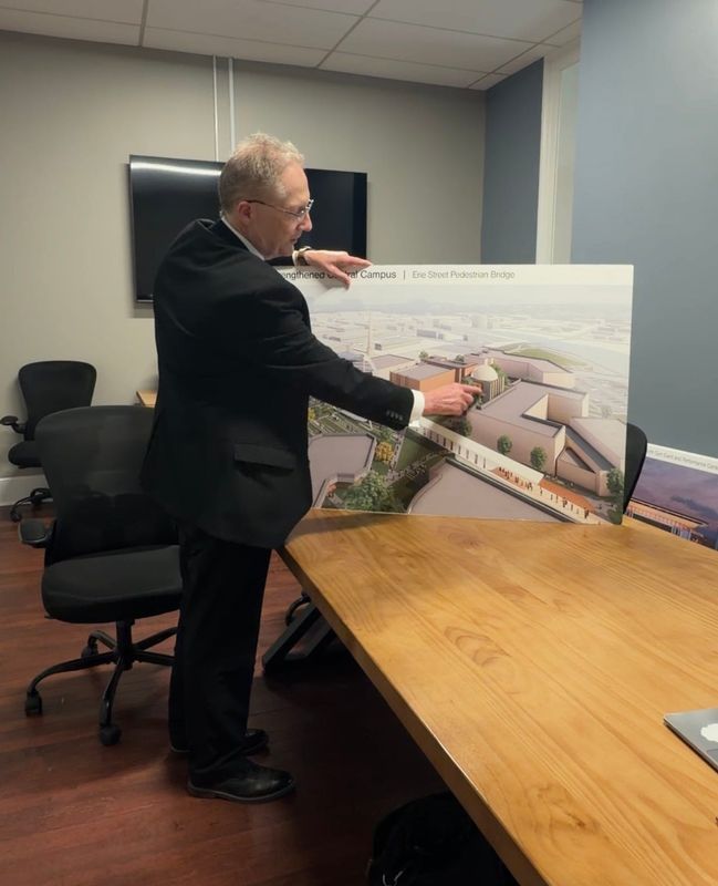 Kirk Kramer, president of St. Clair County Community College, points to a rendering of a proposed pedestrian bridge, planetarium and concert hall as part of a long-term campus plan on April 14, 2026, in Port Huron.