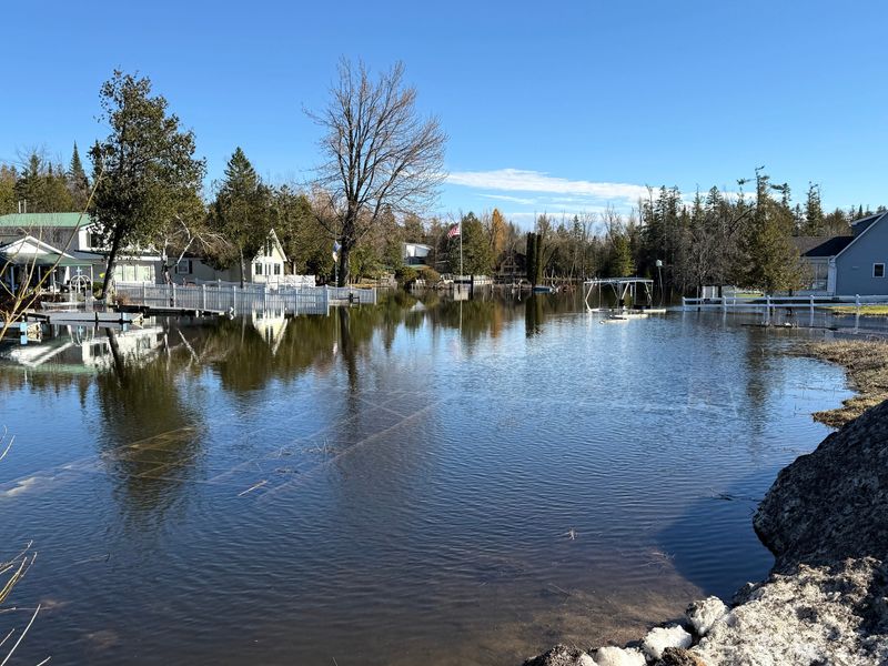 The Crooked River floods yards, homes and docks along its banks near the swing bridge in Alanson on April 16, 2026.