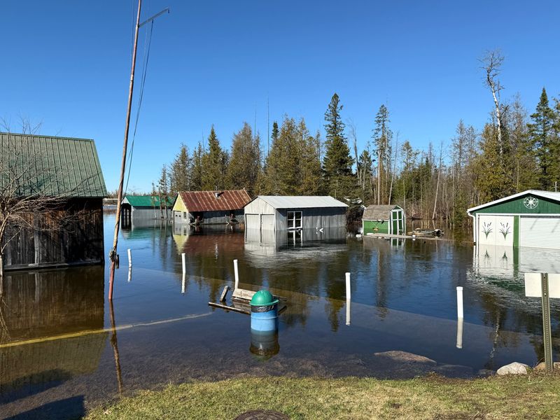 The Crooked River floods park areas, sidewalks and buildings along its banks near the swing bridge in Alanson on April 16, 2026.
