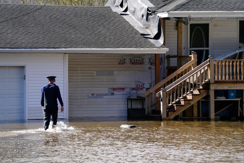 Michigan State trooper Maxwell Nichols walks through the flood waters of the Muskegon River in Cedar Creek Township looking for residents that didn’t evacuate on Friday, April 17, 2026. Nichols was warning that the river was continuing to rise.