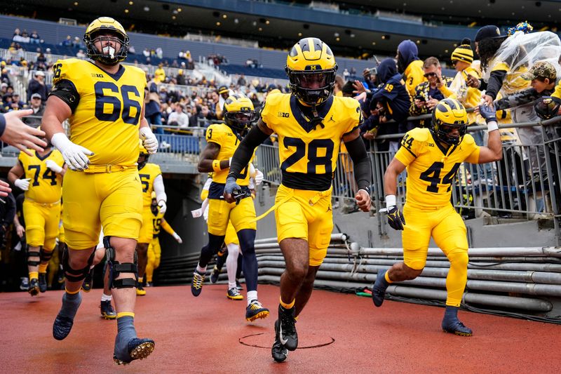 From left, Michigan offensive lineman Dan Taraboi (66), wide receiver I'Marion Stewart (28) and tight end Eli Owens (44) take the field for the spring game at Michigan Stadium in Ann Arbor on Saturday, April 18, 2026.