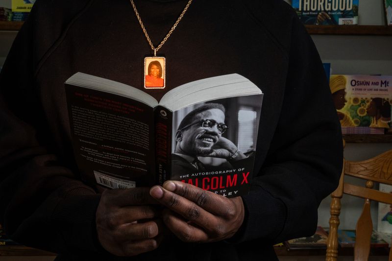 Howard Family Bookstore owner Jerjuan Howard wears a necklace with a photo of his late mother while posing for a photo on Thursday, April 9, 2026, inside of the bookstore he will be opening on Detroit’s west side.