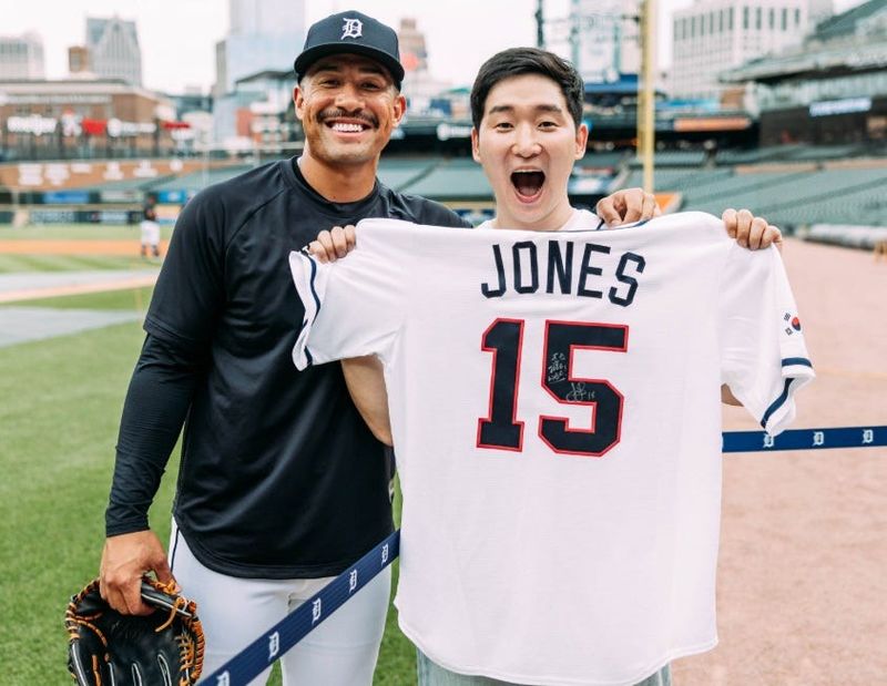 Pistons fan Tom Hur, from South Korea, is presented a Team Korea jersey by Tigers designated hitter Jahmai Jones before Tuesday's game at Comerica Park.